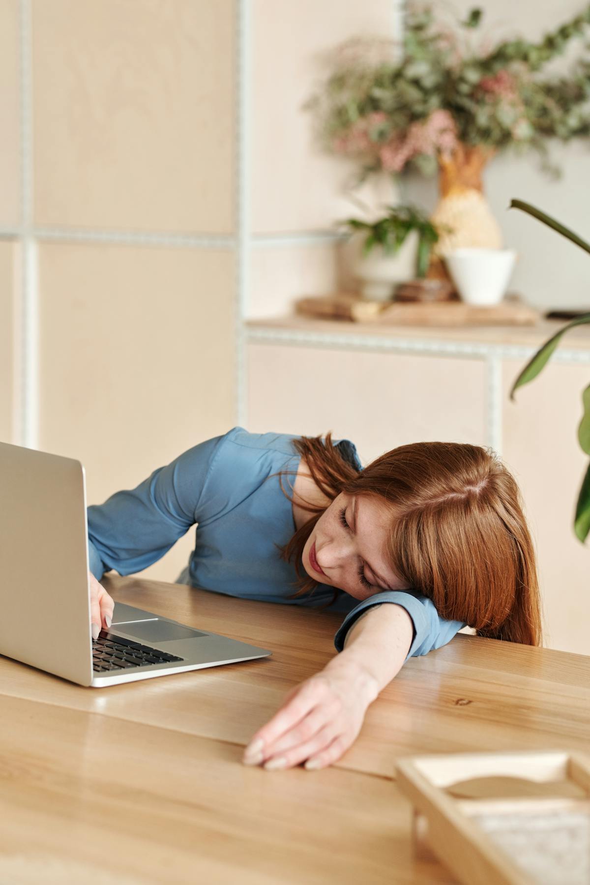 A tired office worker slumped at her desk in the early afternoon, rubbing her eyes